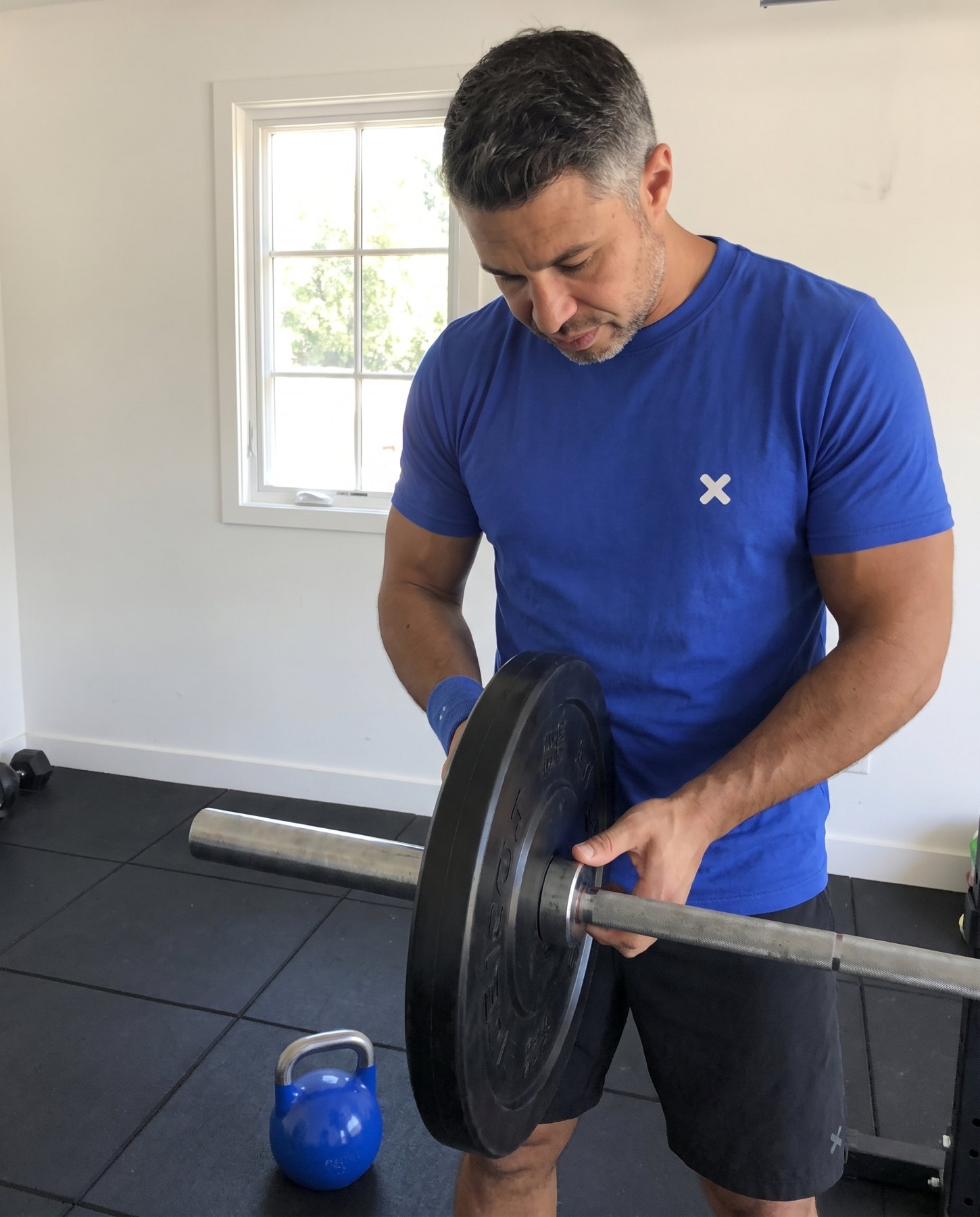 Daniel setting up a barbell in the garage gym used for form videos